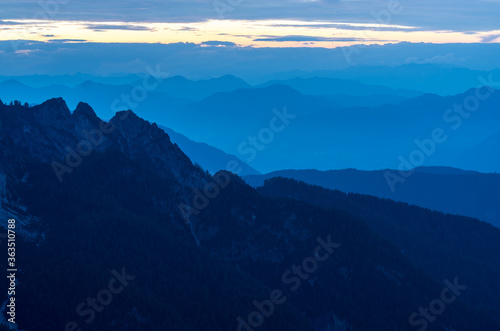 Spectacular view of blue mountain ranges silhouettes and fog in valleys. Julian Alps  Triglav National Park  Slovenia. View from Mountain Slemenova  Sleme.