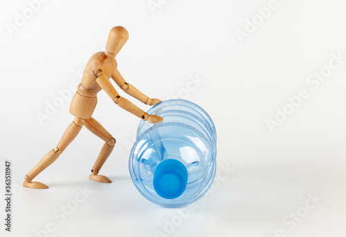 A wooden man rolls an empty five gallon plastic water bottle. Isolated on white on a white background.