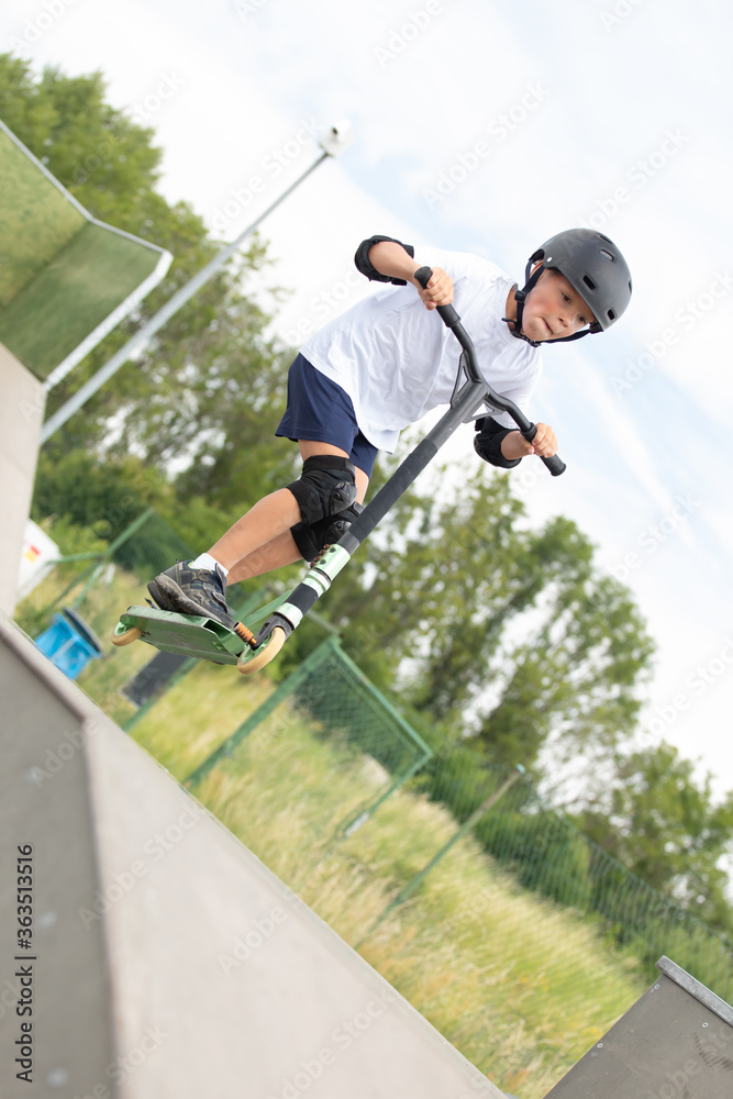 The boy jumps on a scooter.