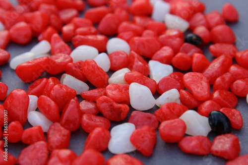 Colorful red and white small pebbles background on dark surface. Beautiful texture background.