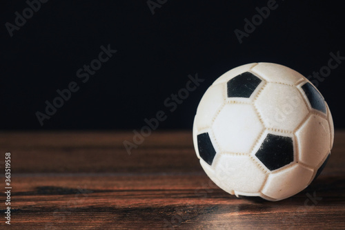 Classic foot ball on dark wood floor in a game hall. Copy space. Dark background.