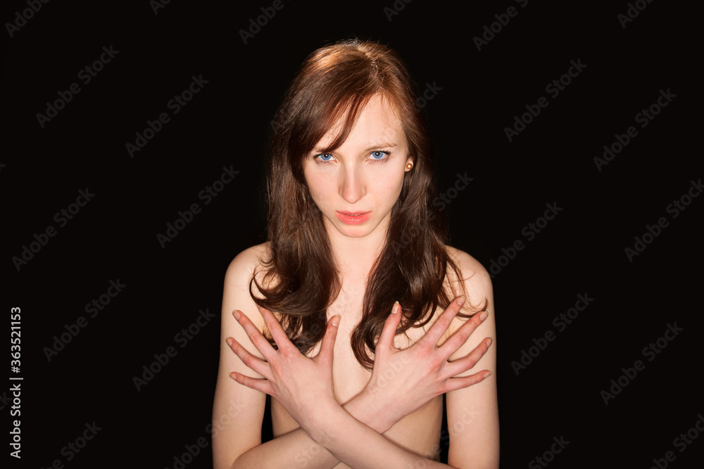 Classic nude of an attractive young woman hiding her breasts with her hands in front of black studio background Classic nude of an attractive young woman hiding her breasts with her hands in front of black studio background
