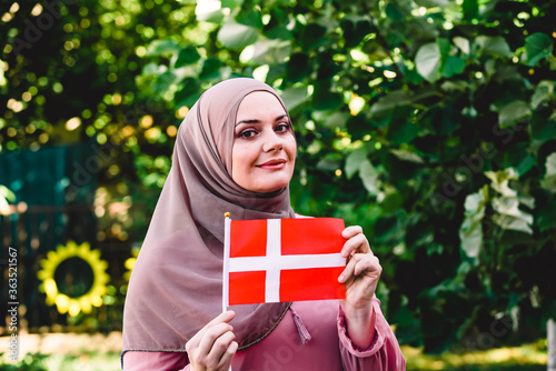 Muslim woman in hijab holds flag of Denmark