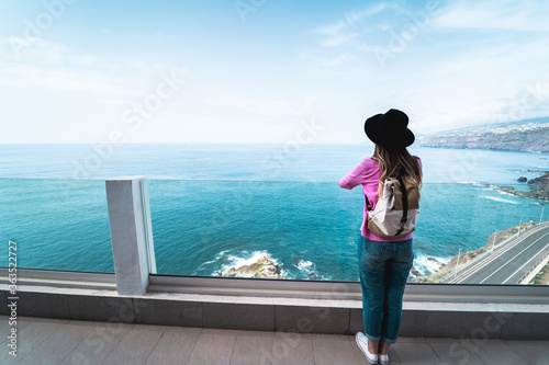 Young woman tourist with ocean view in background - Travel hipster girl feeling happy and free on summer vacation - Holiday, wanderlust and trip trends concept - Main focus on backpack