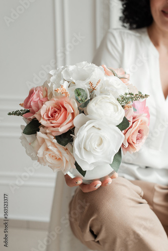 Artificial flowers in a girl's hands. Decorative flowers as a gift. Florist makes flowers. Decorative flowers and hands of a girl.