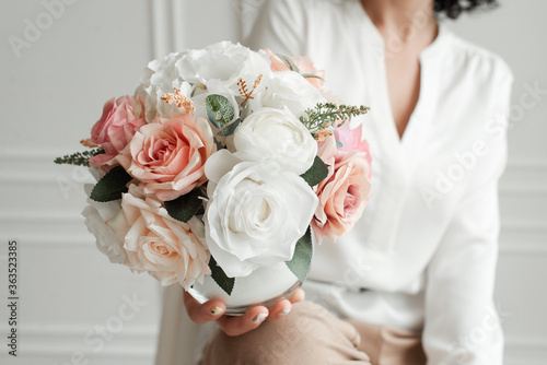 Artificial flowers in a girl's hands. Decorative flowers as a gift. Florist makes flowers. Decorative flowers and hands of a girl.