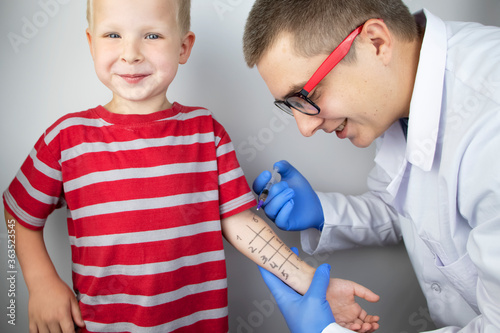 An allergist doctor makes a skin test for allergies. The boy is being examined in the laboratory, waiting for a reaction to allergens. photo