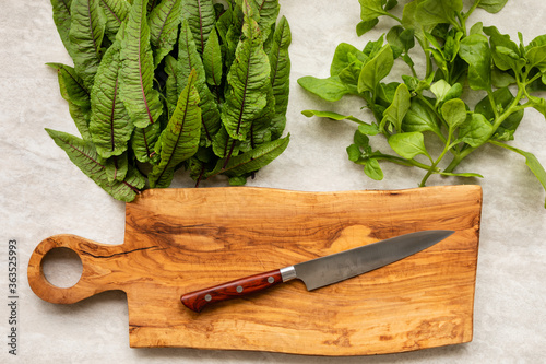 Fresh leafy vegs: New Zealand spinach (Tetragonia tetragonoides) and Bloody dock (Rumex sanguineus) and wooden board with Japanese handmade knife. Top view. photo