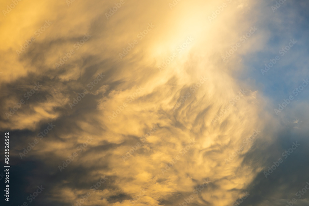 Rolling golden clouds on overcast sky during sunset.