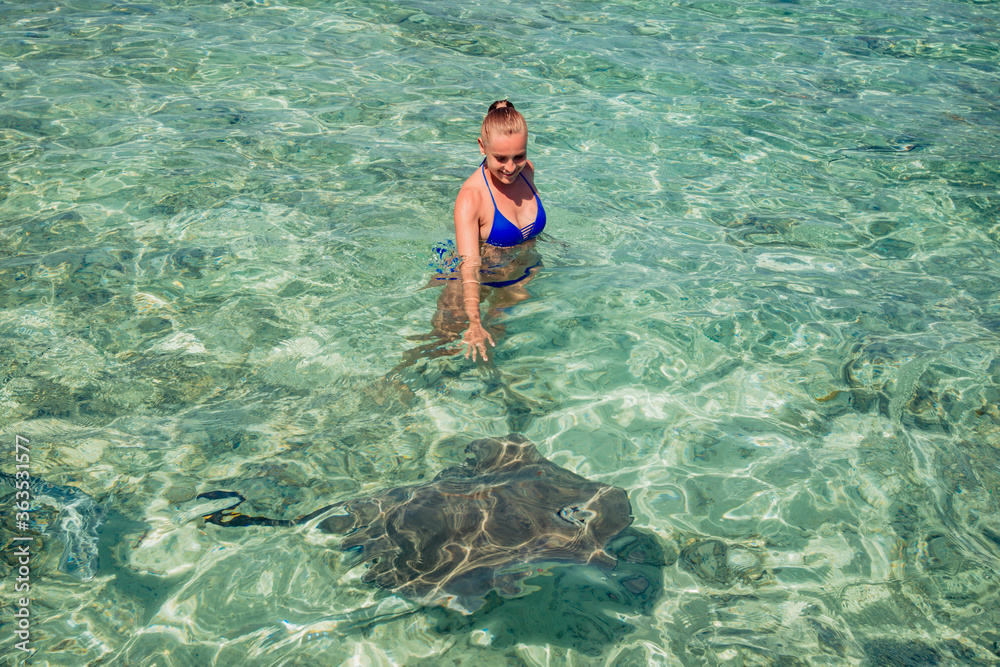 happy young girl swimming with two Stingray in ocean