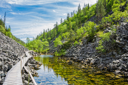 View of The Pyha-Luosto National Park in summer, rocks, stones, trees, wooden walkway and natural pond, Lapland, Finland