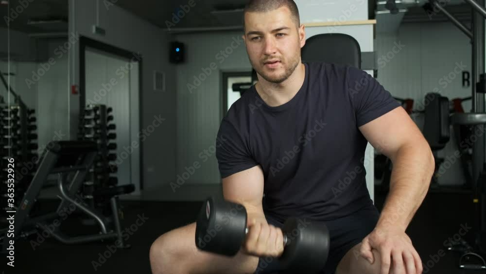Healthy pumped athlete of Caucasian appearance and athletic figure shakes biceps in the gym Healthy pumped athlete of Caucasian appearance and athletic figure shakes biceps in the gym