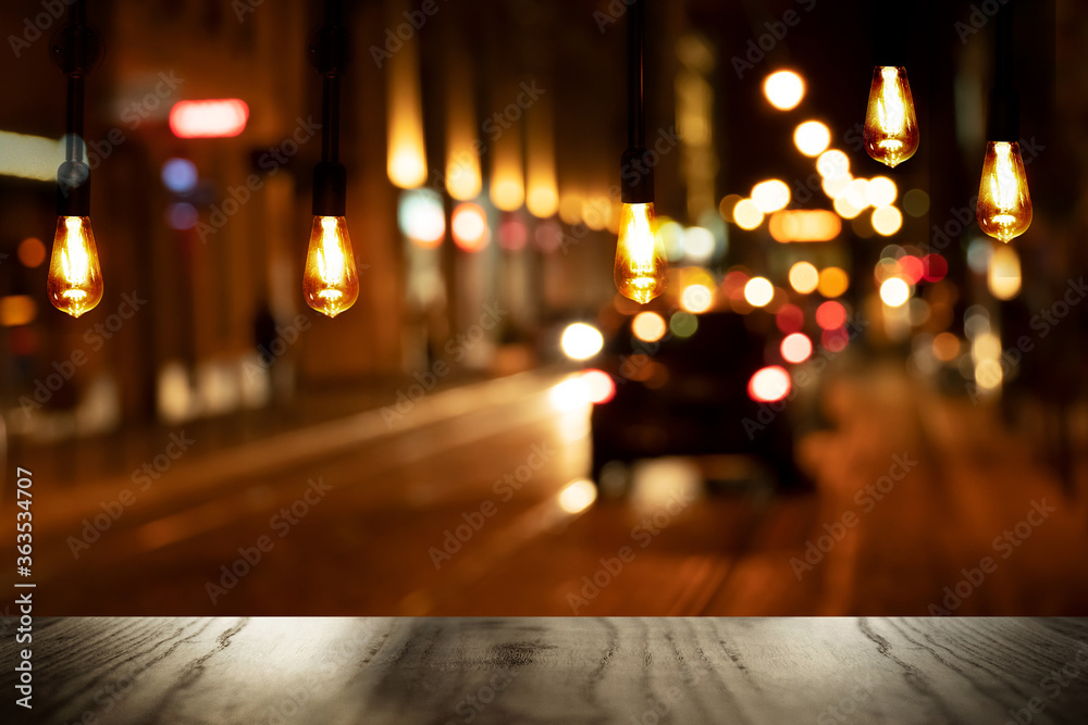 top of black wood bar table and retro lamp with city street night light scene background