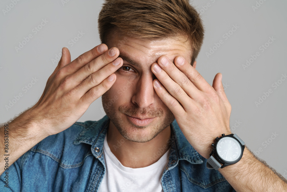 Portrait of pleased unshaven man smiling and covering his eyes Portrait of pleased unshaven man smiling and covering his eyes