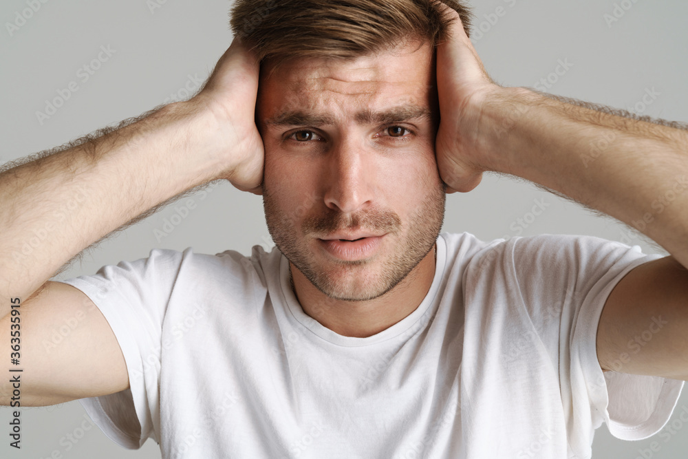 Portrait of redhead man looking at camera while grabbing his head