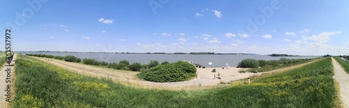 cycling on dyke along Elberadweg near Gruenendeich, Lower Saxony, Germany, panoramic view photo