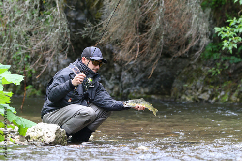 Fisherman in action fight against a trout. Fishing scene. Catch of fish
