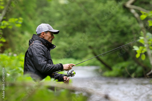Fisherman hunting salmon fish. Outdoor fishing in river during rain. Hunting and hobby sport. © Michal