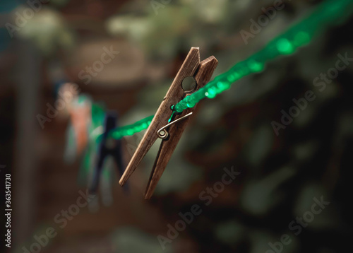 An old wooden clothespin hanging from a wet clothesline