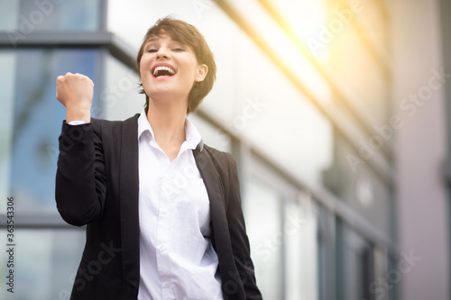 an expressive and happy businesswoman outside