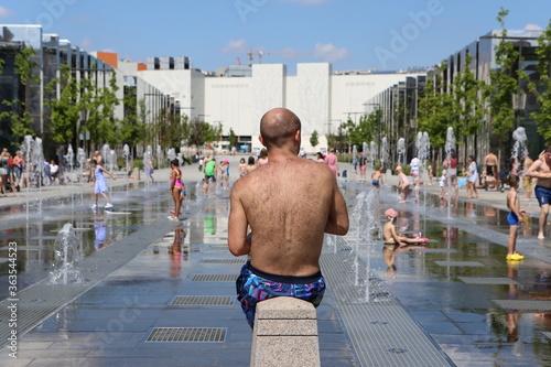 Man with hairy back on Hodynsky Boulevard, Moscow city, Russia. Park Hodynsky Field. Improvement of public spaces. Summer fountain, active children's water games. Heat photo