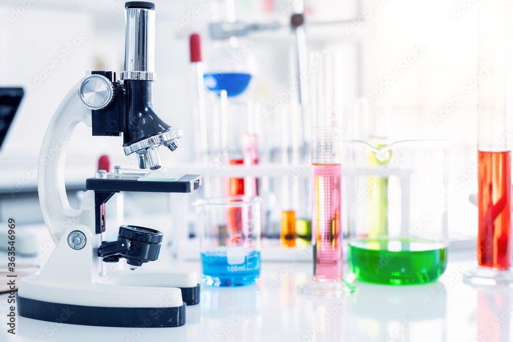 Microscope and test tubes with lab glassware in laboratory background, research and Scientific concept Microscope and test tubes with lab glassware in laboratory background, research and Scientific concept