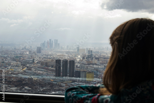 Russia, Moscow, 2019: Ostankino TV tower, a girl admiring the view of a huge city