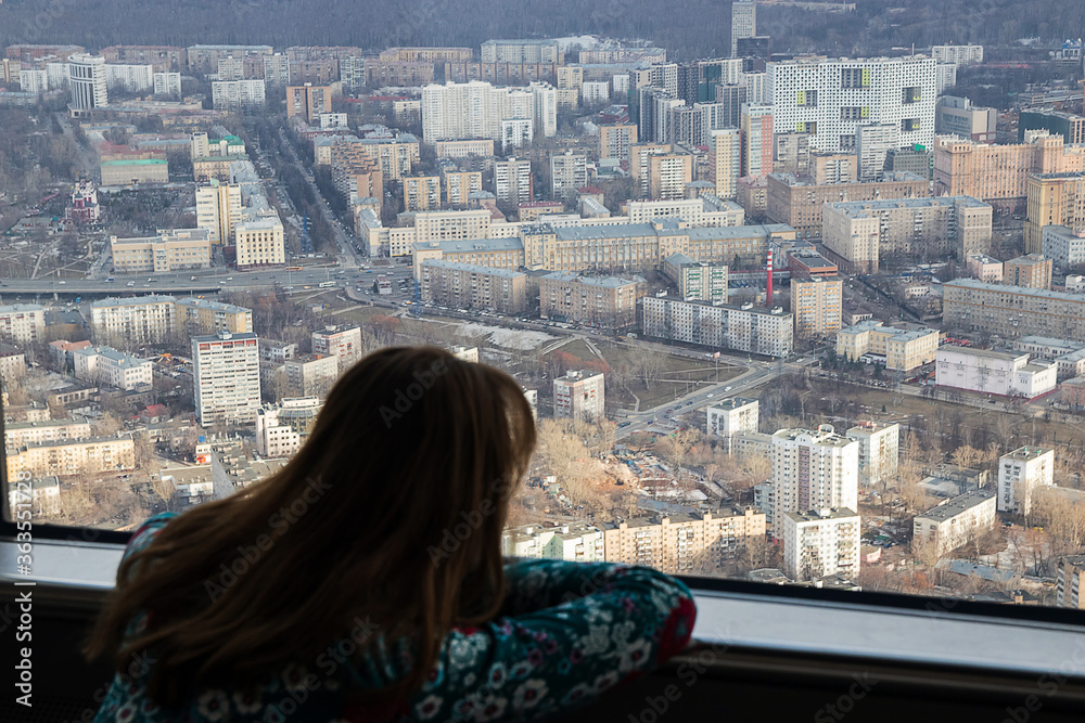 Russia, Moscow, 2019: Ostankino TV tower, a girl admiring the view of a huge city