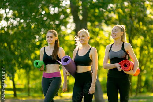 Group of woman prepare and chatting before yoga exercise outdoor on a bright morning in the park.holding yoga mat