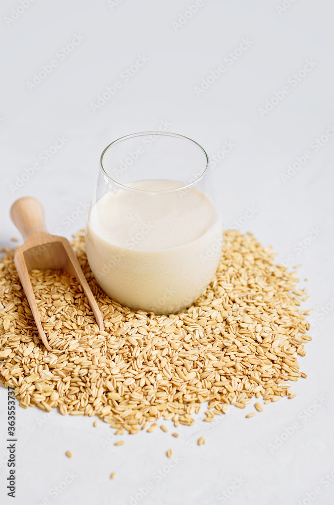 Vegan non dairy alternative oat milk in glass. Oat cereal in wooden spoo on stone table. concept of vegetarian diet eating, dieting, sport and fitness menu Vegan non dairy alternative oat milk in glass. Oat cereal in wooden spoo on stone table. concept of vegetarian diet eating, dieting, sport and fitness menu