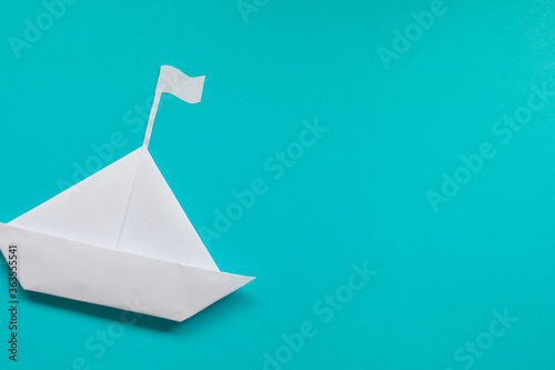 White paper ship on blue background. Copy space.