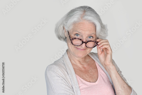 Portrait of senior woman with eyeglasses standing on white background, isolated