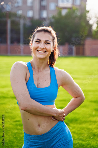 Athletic muscled young woman in a sports wearing doing fitness exercises. Fitness woman posing at the stadium. Healthy athletic lifestyle