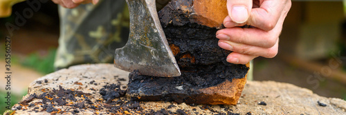 men's hands with an axe clean chaga mushroom birch fungus in the fresh air. step by step. banner