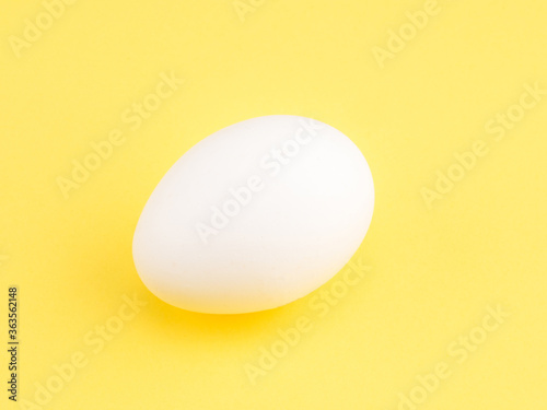 One white chicken egg on a yellow background. Healthy eating concept