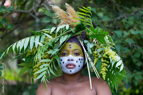 Foto Portrait of young African-American woman with face paint and foliage headdress i