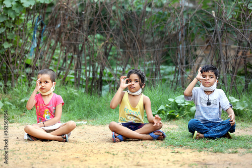 3 Indian kids in mask practicing yoga in natural green background.Yoga with nature. Boosting immunity with yoga to defeat corona virus. 