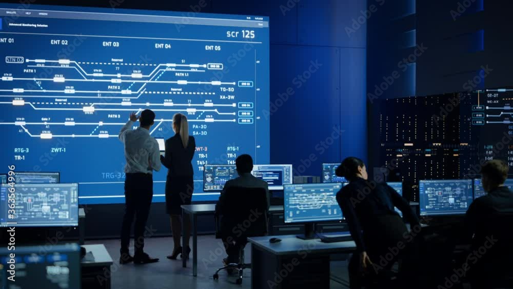 Telecommunications Company System Control and Monitoring Room with Diverse Team of Professionals Working on Personal Computers. Big Screen Display Showing Infrastructure Infographics and Data Telecommunications Company System Control and Monitoring Room with Diverse Team of Professionals Working on Personal Computers. Big Screen Display Showing Infrastructure Infographics and Data