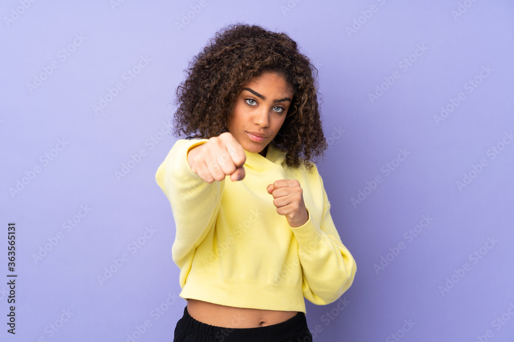 Young African American woman isolated on background with fighting gesture
