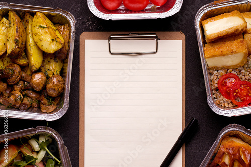 Food Delivery Concept. Empty form next to a vegetarian meal on a black background. Copy space
