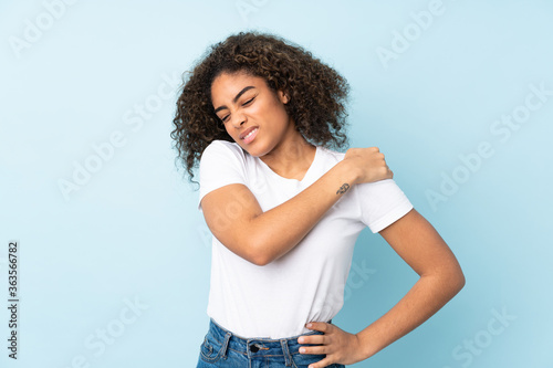 Young African American woman isolated on blue background suffering from pain in shoulder for having made an effort