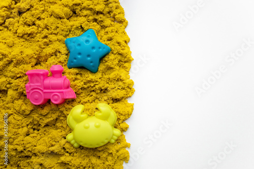 Top view yellow kinetic sand with molds with copy space. Magic sand for children. Selective focus photo