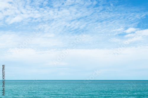 White clouds on blue sky over the calm ocean in sunny day at the Gulf of Thailand. Natural background of beautiful seascape.