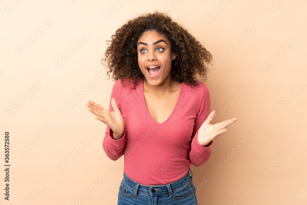 Young African American woman isolated on beige background with surprise facial expression Young African American woman isolated on beige background with surprise facial expression