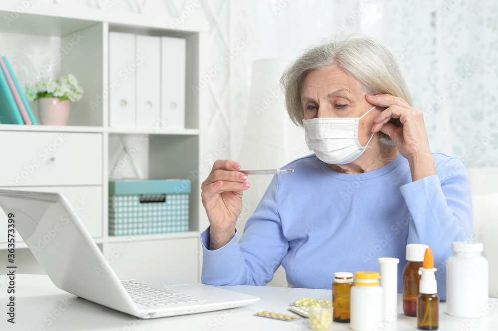 Ill beautiful senior woman with facial mask holding thermometer Ill beautiful senior woman with facial mask holding thermometer