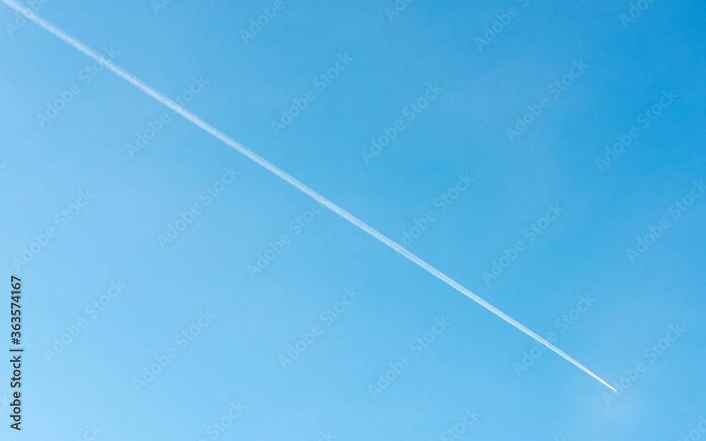 Diagonal contrail of jet plane flying in blue sky Diagonal contrail of jet plane flying in blue sky