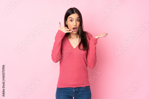 Young caucasian woman over isolated background making phone gesture and doubting