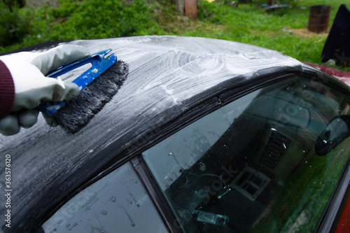 cleaning the tarpaulin roof of the convertible with foam cleaner.