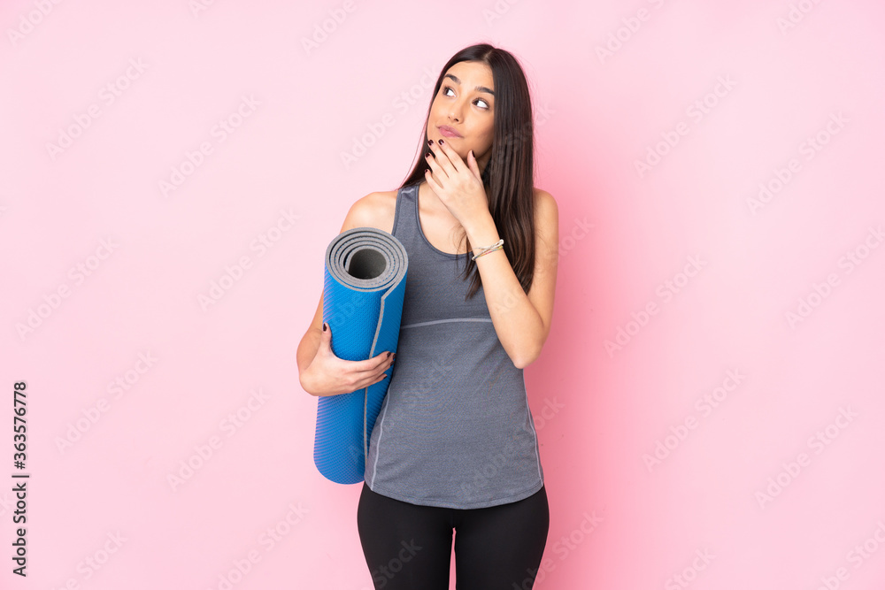 Fototapeta premium Young caucasian woman with mat isolated on pink background thinking an idea