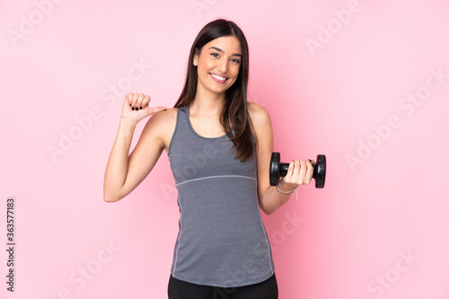 Young woman making weightlifting isolated on pink background proud and self-satisfied © luismolinero